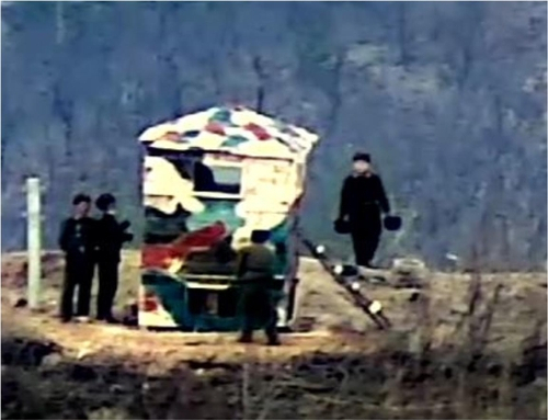 In this file photo released by the Defense Ministry on Nov. 27, 2023, North Korean soldiers are spotted near a guard post being rebuilt with wooden materials inside the Demilitarized Zone. (Defense Ministry)