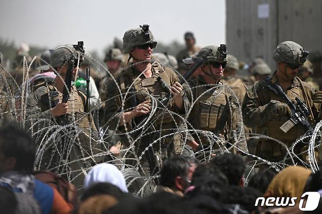 20일 (현지시간) 탈레반이 아프가니스탄을 장악한 뒤 미군들이 카불 공항 인근 도로의 철조망 너머에서 아프간을 탈출하려는 아프간인들을 바라보고 있다. ⓒ AFP=뉴스1 ⓒ News1 우동명 기자