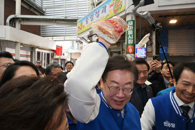 더불어민주당 이재명 대표가 24일 서울 송파구 잠실 새마을전통시장을 방문해 시민들로부터 빵을 전달받고 있다. 연합뉴스