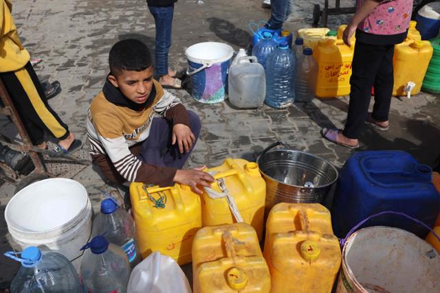 지난 22일 가자지구 최남단 도시 라파에서 팔레스타인 어린이가 물을 얻기 위해 기다리고 있다. 라파=AFP 연합뉴스