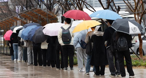 봄비가 내리는 26일 오전 서울 중구 서울광장에서 우산을 쓴 학생들이 학교로 향하는 버스를 기다리고 있다. 뉴스1
