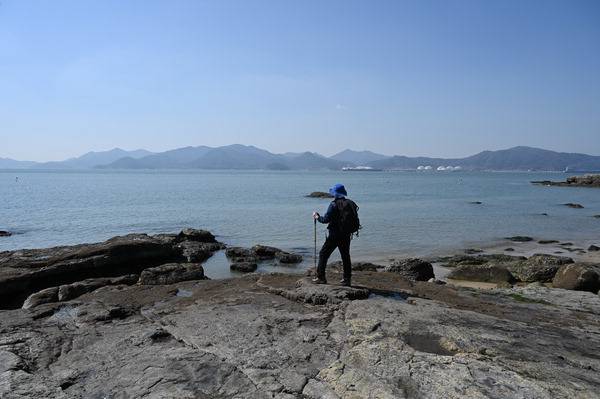 경남 남해군의 해안 둘레길은 남해 바래길 13코스와 남파랑길 45코스가 겹친다. 취재팀이 예계항을 지나 나오는 해안가 암반에서 여수만 건너 여수시를 바라 보고 있다. 왼쪽은 봉화산 부암산이며 오른쪽 제석산과 사이에는 진달래 산행으로 잘 알려진 영취산이다.