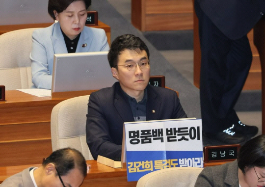 김남국 무소속 의원이 지난해 12월 28일 오후 국회 본회의에서 김건희 여사 특검법 수용을 촉구하는 손팻말 뒤에 앉아있는 모습. 연합뉴스