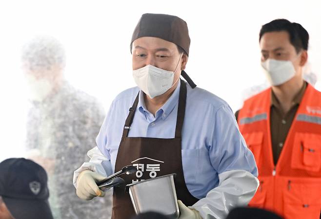 윤석열 대통령이 지난 27일 서울 명동성당 내 무료 급식소인 '명동밥집' 야외 배식장에서 봉사활동을 펼치며 추가 배식 희망자를 찾아 오가고 있다. ⓒ대통령실 제공