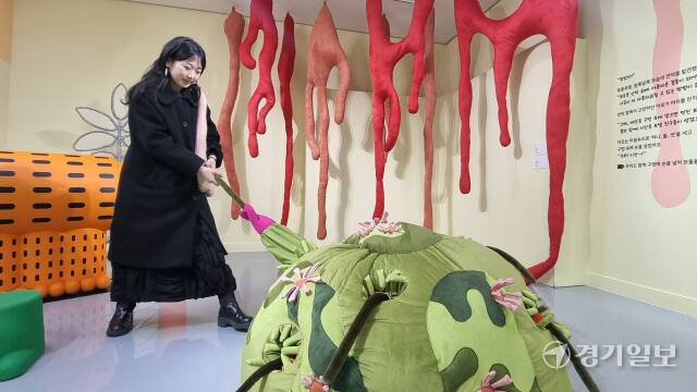 현대사회 속 ‘반려’의 다양한 모습을 상상할 수 있는 수원시립미술관의 ‘쿵짝공원 속 친친’ 전시회가 지난 14일 개막한 가운데 깪 작가가 신작 ‘꽃이 핀 언덕’(2024, 화면 하단)의 체험 예시를 보여주고 있다. 이나경기자