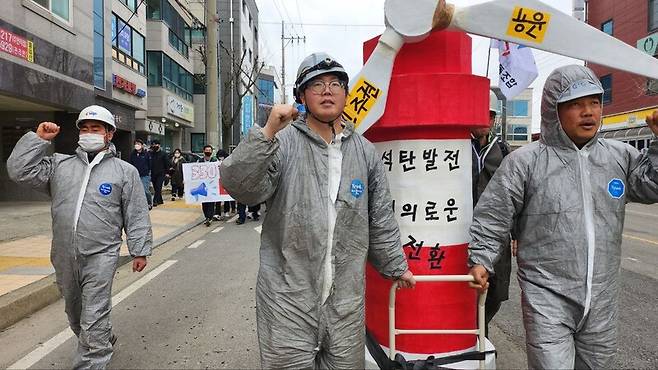 태안화력발전소 2차 하청 노동자인 김영훈(가운데)씨가 ‘석탄발전소의 정의로운 전환’을 촉구하는 조형물을 들고 태안 시내를 행진하고 있다.