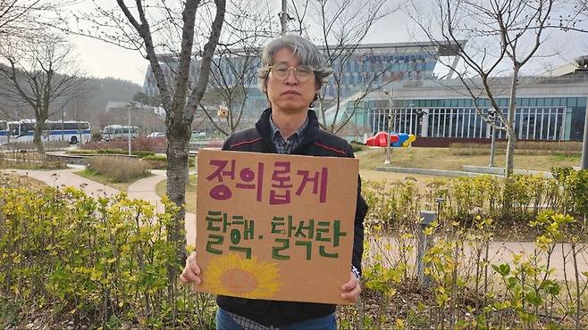 태안화력발전소 1차 하청 노동자인 송상표씨가 지난 30일 충남 태안 서부발전 본사 앞에서 ‘정의로운 탈석탄’을 요구하는 팻말을 들고 있다.