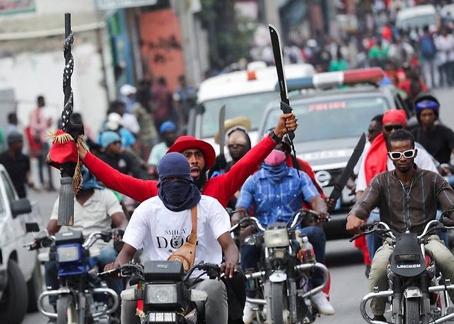 2월5일 아이티 수도 포르토프랭스에서 열린 반정부 집회에서 오토바이를 탄 참가자들이 마체테(날이 넓고 긴 칼)를 손에 든 채 거리를 내달리고 있다. REUTERS