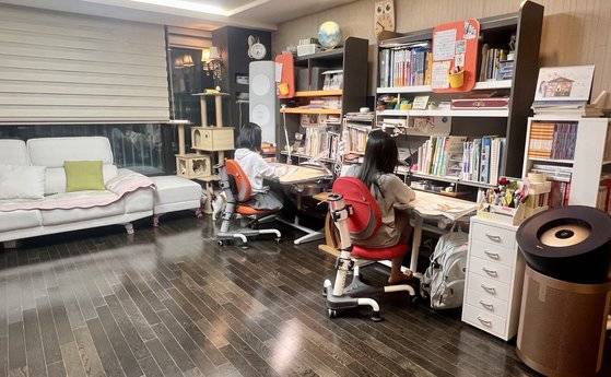 거실 책상 앞에 나란히 앉은 정지영씨의 두 딸. [사진 정지영]