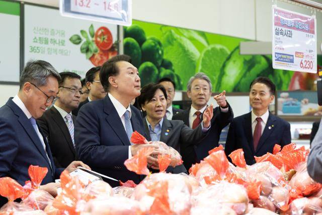 윤석열 대통령이 지난달 18일 서울 서초구 농협하나로마트 양재점 과일매장에서 물가 현장 점검을 하며 농림축산식품부 할인지원 사과를 살펴보고 있다. 대통령실 제공