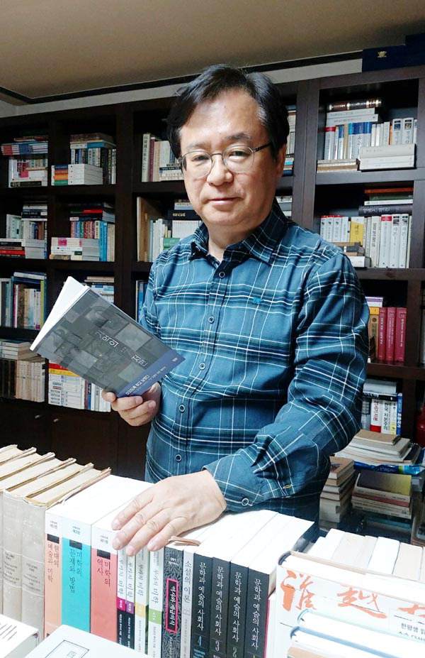 김세화 추리소설 작가가 자신의 책을 들고 서재에서 포즈를 취했다.
