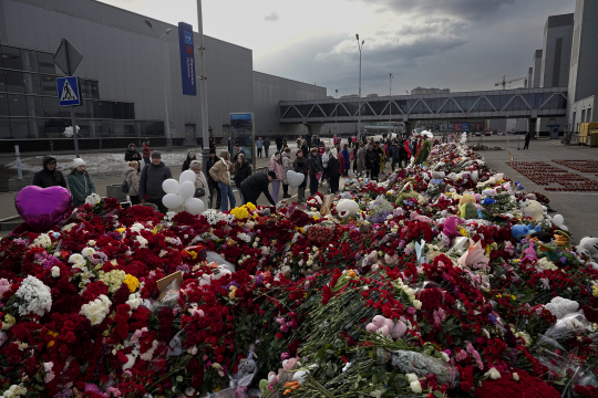 3월 26일(현지시간) 러시아 모스크바 외곽 크로쿠스 시청 테러 현장 인근에 마련된 추모소에서 시민들이 꽃과 장난감을 놓으며 희생자들을 애도하고 있다. AP 뉴시스