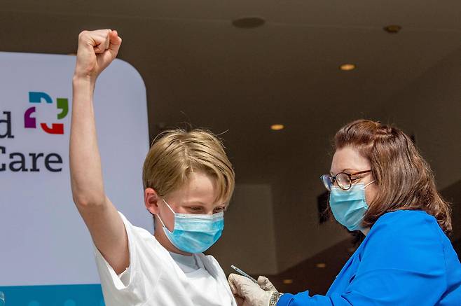 지난 5월 13일 미국 코네티컷주 하트포드 접종센터에서 13살 소년 찰즈 무로가 백신접종을 한뒤 주먹을 쥐어 올리며 축하하고있다. 미국은 12세에서 15세 사이 어린이도 화이자-바이오엔테크 백신접종을 받을 수 있다./AFP 연합뉴스