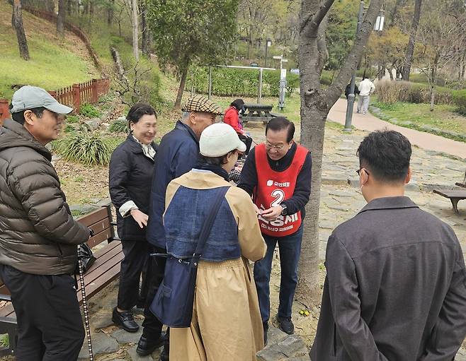 6일 오전 서울 용산 선거구의 국민의힘 권영세 후보가 용산구 효창공원 안에서 나들이를 나온 한 가족과 인사를 나누고 있다. /권순완 기자