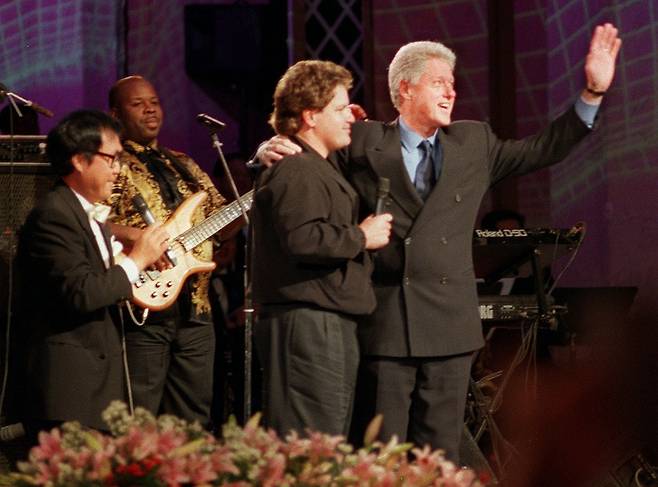 1998년 11월 21일 빌 클린턴 미국 대통령이 세종문화회관에서 녹화된 KBS 열린음악회 '한미 우정의 콘서트'에서 가수인 동생 로저 클린턴의 어깨에 오른손을 두르고 기립박수를 보내는 참석자들에게 손을 흔들어 인사하고 있다./조선일보 DB