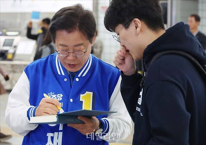 이재명 더불어민주당 인천 계양을 후보가 8일 오전 인천 계양구 임학역에서 한 시민의 민법입문 교재에 '훌륭한 법조인 되시기 바랍니다'라고 격려의 말을 적고 있다. ⓒ데일리안 홍금표 기자