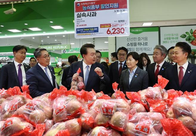 윤석열 대통령이 지난 3월 18일 서울 서초구 농협 하나로마트 양재점 과일 매장에서 농림축산식품부 할인 지원 사과를 살피며 과일 물가 현장 점검을 하고 있다. [대통령실통신사진기자단]  연합뉴스