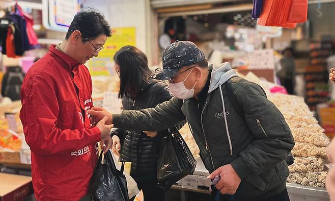 부산 해운대구 좌동재래시장에서 한 주민이 주진우 전 대통령실 비서관(왼쪽) 선거 점퍼에 적힌 이름을 확인하고 있다. [제공=주진우 예비후보 선거사무소]