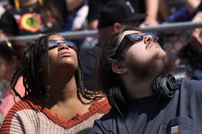 8일(현지시간) 미국 일리노이주 카본데일의 서던 일리노이 대학교 캠퍼스에서 사람들이 개기일식의 시작을 지켜보고 있다. [AFP]