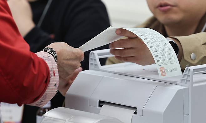제22대 국회의원선거 사전투표 둘째날인 지난 6일 서울 중구 명동주민센터에 마련된 사전투표소에서 한 유권자가 투표용지를 받고 있다. 연합뉴스