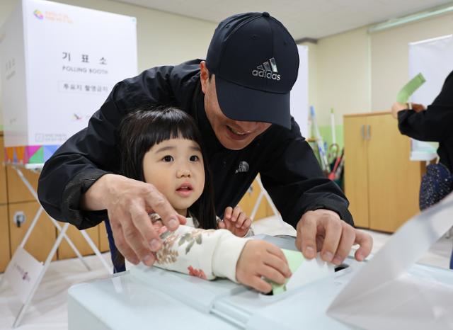 제22대 국회의원 선거일인 10일 오전 인천 미추홀구 용현여자중학교에 마련된 용현5동 제6투표소에서 한 어린이가 아빠와 함께 투표지를 투표함에 넣고 있다. 연합뉴스