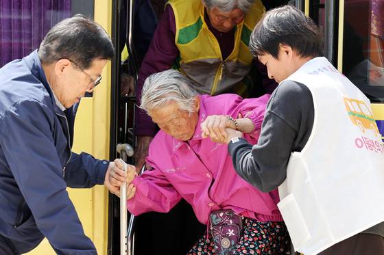 An elderly citizen gets assistance departing a bus on her way to vote at a polling station in Gokseong-gun, North Jeolla, on Wednesday. [YONHAP]