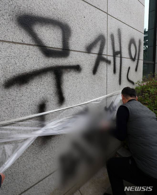 [서울=뉴시스] 김명년 기자 = 11일 오후 서울 서초동 서울고등검찰청 건물에 문재인 전 대통령과 서훈 전 국가정보원장을 비방하는 내용의 낙서를 하고 건물 창문에 돌을 던진 40대 남성이 경찰에 붙잡혔다. 사건 현장에서 청사 관계자들이 비닐막으로 낙서를 가리고 있다. 2024.04.11. kmn@newsis.com