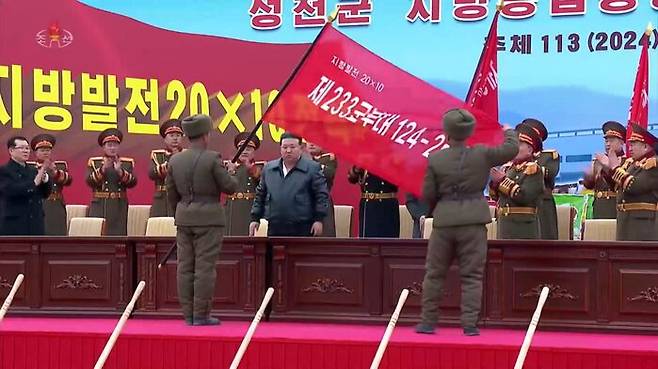김정은이 지방공장 건설을 담당할 군부대에 깃발을 수여하고 있다.