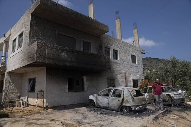 13일(현지시간) 요르단강 서안지구 알무가이르 마을에 있는 집과 차가 그을려져 있다. AP연합뉴스
