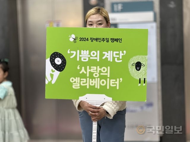 선한목자교회 봉사자가 14일 경기도 성남시 교회 승강기 앞에서 '기쁨의 계단 사랑의 엘리베이터' 캠페인 팻말을 들고 있다.