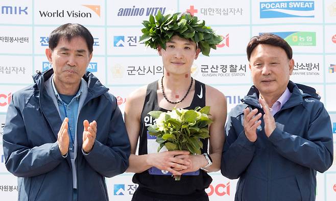 14일 전북 군산에서 열린 ‘2024 군산 새만금 국제마라톤대회’ 남자 엘리트 풀코스에서 1위로 골인한 인천광역시청 소속 김재민이 월계관을 쓰고 강임준 군산시장(오른쪽) 등과 기념 촬영하고 있다. 군산시 제공