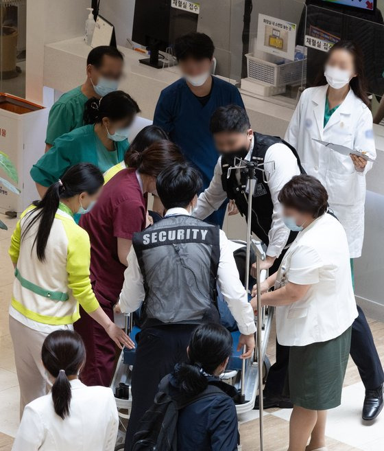 정부의 의대 정원 확대에 반발하는 전공의를 비롯한 의료계의 집단행동이 이어지고 있는 16일 오전 서울 소재 대학병원 로비에서 한 시민이 쓰러지자 의료진들이 응급처치를 하고 있다. [뉴스1]