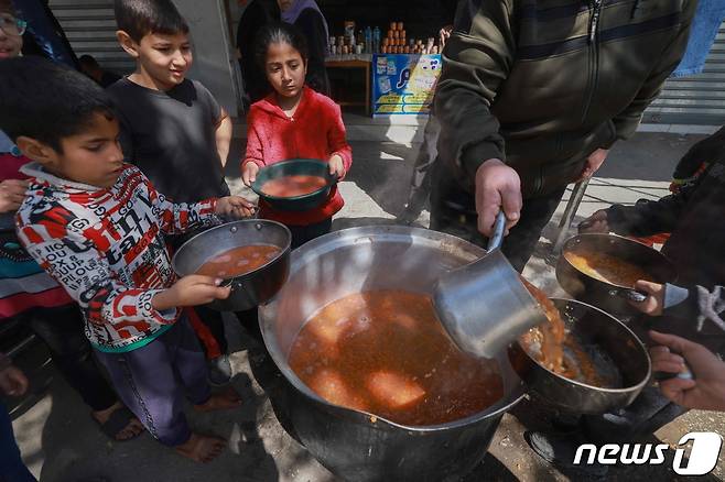지난달 5일(현지시간) 가자지구 남부 라파에서 팔레스타인인 아동들이 그릇을 들고 음식을 나눠받고 있다. 이스라엘과 팔레스타인 무장 정파 하마스 간 전쟁으로 가자지구 아동들은 심각한 굶주림에 시달리고 있다. 2024.03.05/ ⓒ AFP=뉴스1 ⓒ News1 권진영 기자