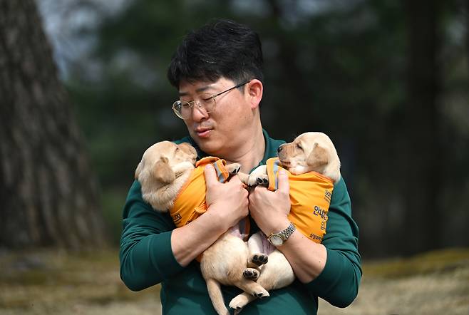 Park Tae-jin holds two puppies at Samsung Guide Dog School in Yongin, Gyeonggi Province, March 27. (Im Se-jun/ The Korea Herald)