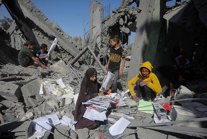 폐허 속 공부할 책 찾는 어린이들 20일(현지시간) 가자지구 최남단 국경도시 라파에서 팔레스타인 아이들이 전날 밤 이스라엘군의 폭격으로 파괴된 주택 잔해에서 물건들을 찾고 있다. UPI연합뉴스