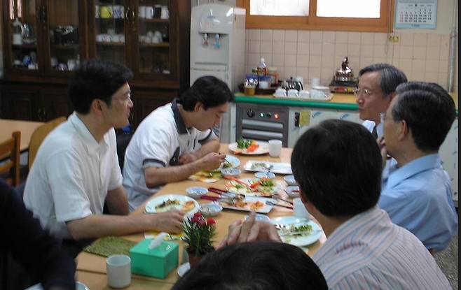이재용 삼성전자 회장(당시 상무·맨 왼쪽)이 2003년 서울 영등포 요셉의원을 찾아 관계자들과 함께 식사를 하고 있다. 이 회장은 두 번째 방문부터는 검소한 티셔츠 차림으로 이곳을 찾은 것으로 전해진다.  책 '의사 선우경식'