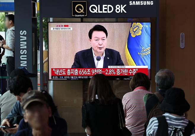 29일 오전 서울역 대합실에서 시민들이 윤석열 대통령이 657조원 규모의 2024년 예산안을 발표하는 장면을 지켜보고 있다./뉴스1