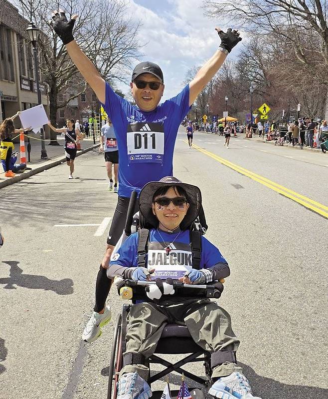 포기는 없다 - 지난 15일(현지 시각) 미국 보스턴 마라톤에 출전한 배종훈씨가 아들 배재국씨의 휠체어를 밀며 15마일(약 24㎞) 정도 지난 지점에서 한 외국인이 카메라를 들이대자 풀쩍 뛰며 포즈를 취했다. /배종훈씨 제공