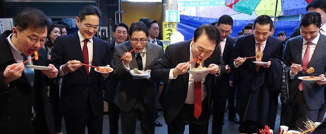 윤석열 대통령이 지난 6일 부산 중구 깡통시장에서 이재용 삼성전자 회장 등 기업 총수들과 떡볶이 등 분식을 시식하고 있다. 왼쪽부터 최재원 SK 수석부회장, 이재용 삼성전자 회장, 조현준 효성그룹 회장, 윤 대통령, 구광모 LG그룹 회장, 김동관 한화그룹 부회장, 정기선 HD현대 부회장./연합뉴스