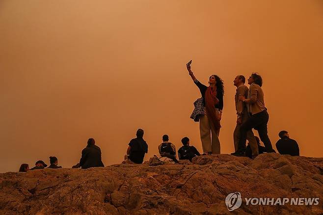 주황색 도시 된 그리스 아테네  (아테네 EPA=연합뉴스) 23일(현지시간) 그리스 아테네가 사하라 사막발 황사로 뒤덮인 가운데 사람들이 아크로폴리스를 산책하고 있다. 2024.04.23 photo@yna.co.kr
