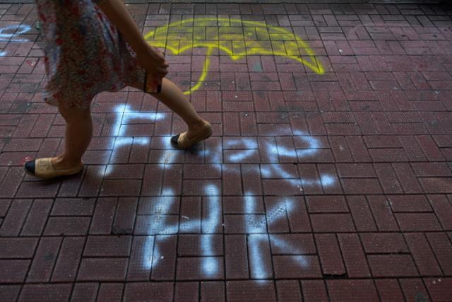 2019년 '우산 혁명 5주년'을 맞아 홍콩에서 반중시위가 격렬해진 가운데 한 시민이 노란 우산과 자유 홍콩이 그려진 길을 걸어가고 있다. AFP 연합뉴스