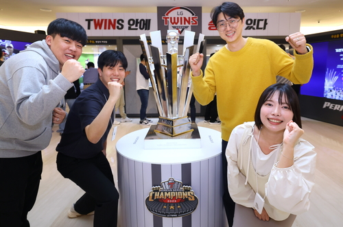 LG트윈스 챔피언 팝업을 찾은 LG 직원들이 2023년 한국시리즈 우승 트로피 레플리카 옆에서 기념 포즈를 취하고 있다.