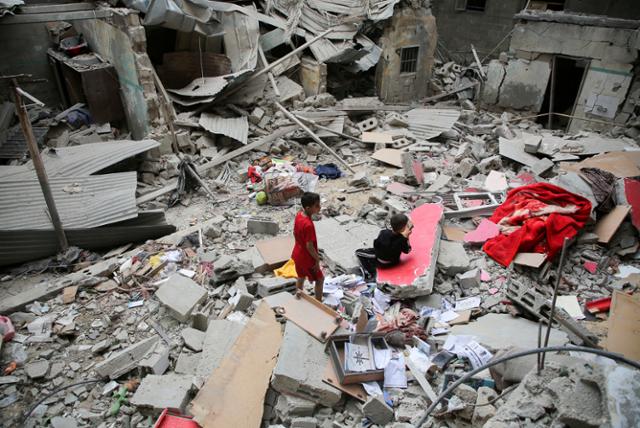 27일 가자지구 남부 라파에서 무너진 건물 위로 팔레스타인 아이들이 보이고 있다. 라파=로이터 연합뉴스