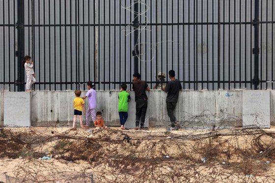 펜스 너머 이집트 군인을 바라보고 서있는 팔레스타인 최남단 라파의 어린이와 청소년들. AFP=연합뉴스