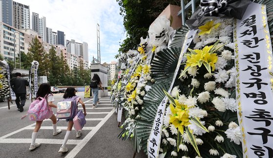지난해 9월 서울 서초구 서이초에서 학생들이 등교하는 모습. 교문 앞에는 추모 화환이 놓여 있다. 뉴스1