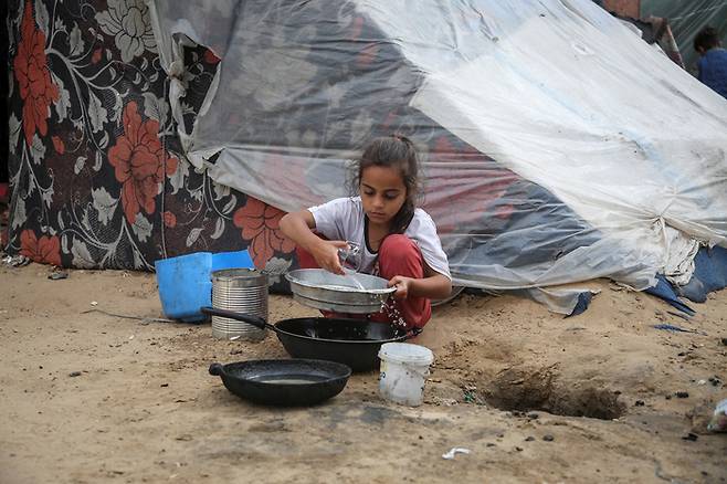 한 팔레스타인 소녀가 27일(현지시간) 가자지구 남부 라파 난민촌에서 통에 물을 붓고 있다. 로이터연합뉴스