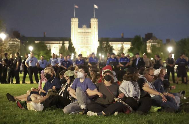 미국 전역에서 불붙은 팔레스타인 지지 시위에 참가한 미주리주 세인트루이스에 있는 워싱턴대 학생들이 27일 밤(현지시간) 자신들을 체포하려는 경찰에 맞서 팔짱을 낀 채 캠퍼스에 앉아 있다. AP연합뉴스