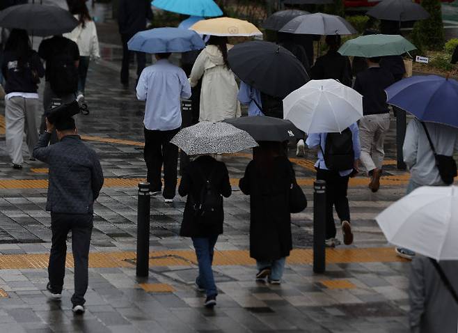 지난 24일 서울 중구 서울시청 인근에서 한 시민이 가방을 머리에 얹고 이동하고 있다. (사진=연합뉴스)