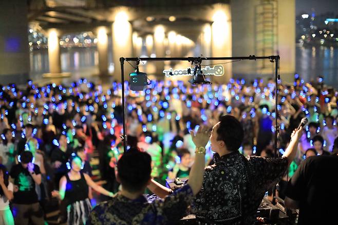 A "noise-free DJ party" takes place at the Han River in 2023, where participants enjoy dance parties wearing wireless headphones. (AHHA Labs)