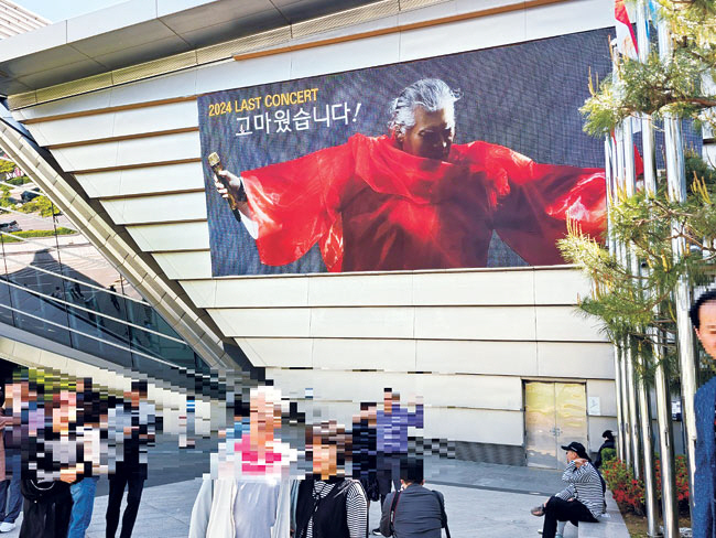 가수 나훈아의 은퇴 콘서트장 앞에 걸린 대형 포스터 앞에서 팬들이 기념 사진을 찍고 있다.  인천=안진용기자